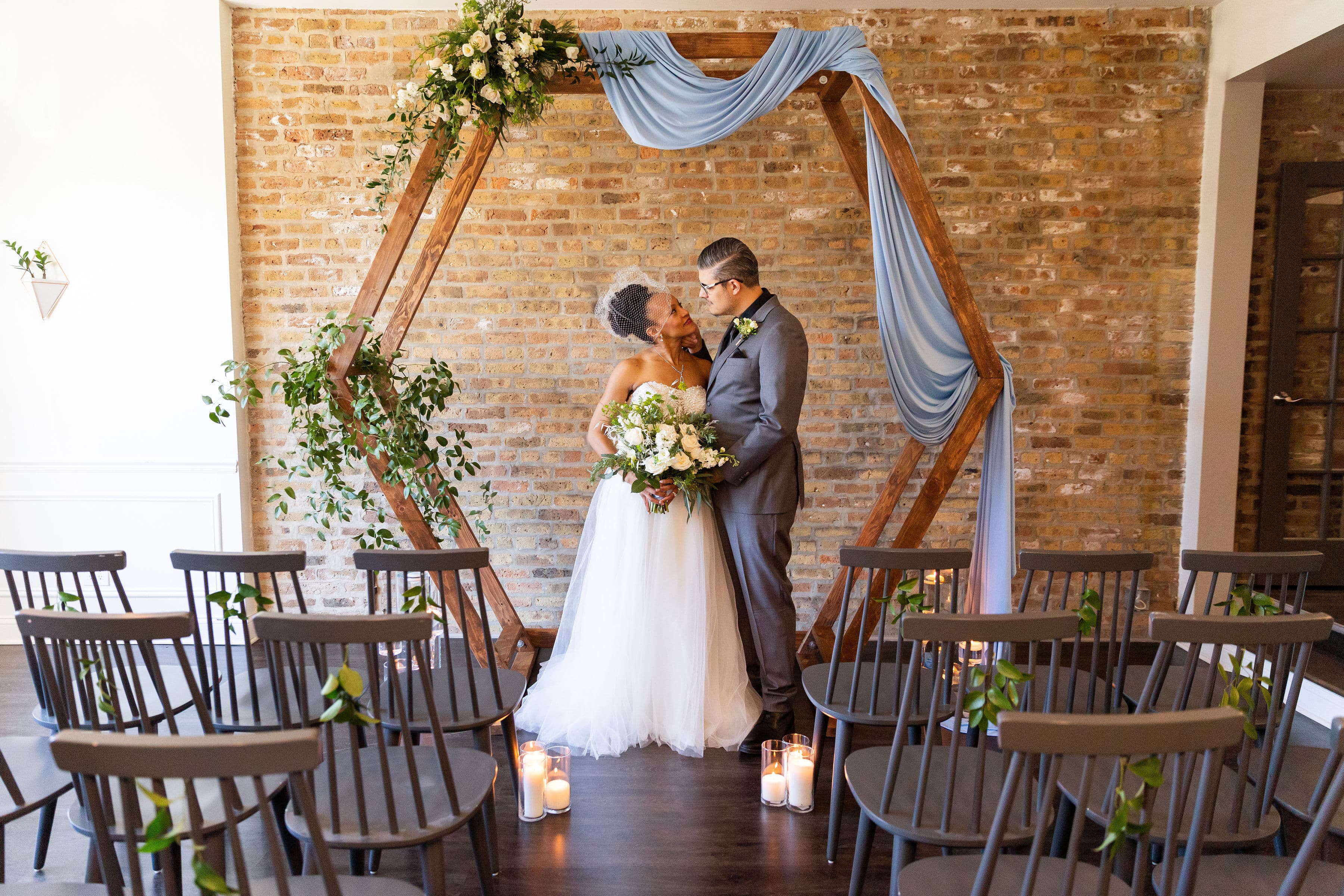 Intimate micro wedding ceremony at Wicker Park Inn in Chicago, featuring a couple exchanging vows beneath a floral and draped hexagonal arch in a cozy brick-walled venue. Intimate micro wedding ceremony at Wicker Park Inn in Chicago, featuring a couple exchanging vows beneath a floral and draped hexagonal arch in a cozy brick-walled venue.